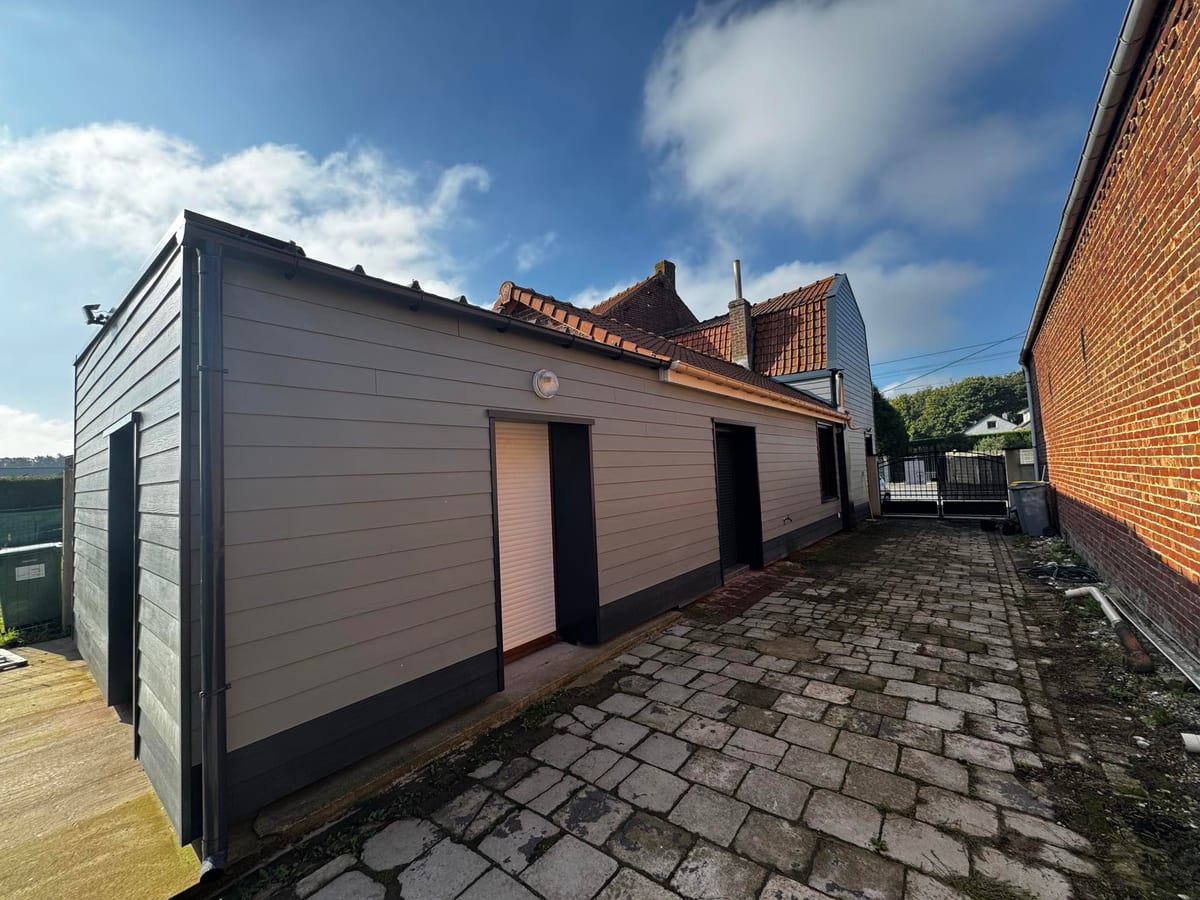 Extension avec bardage taupe et cour pavée rénovée par Hapînov dans le Pas-de-Calais