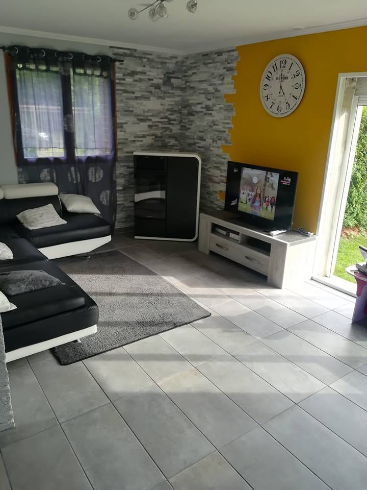 Salon rénové avec mur en parement pierre et accent jaune par Hapînov