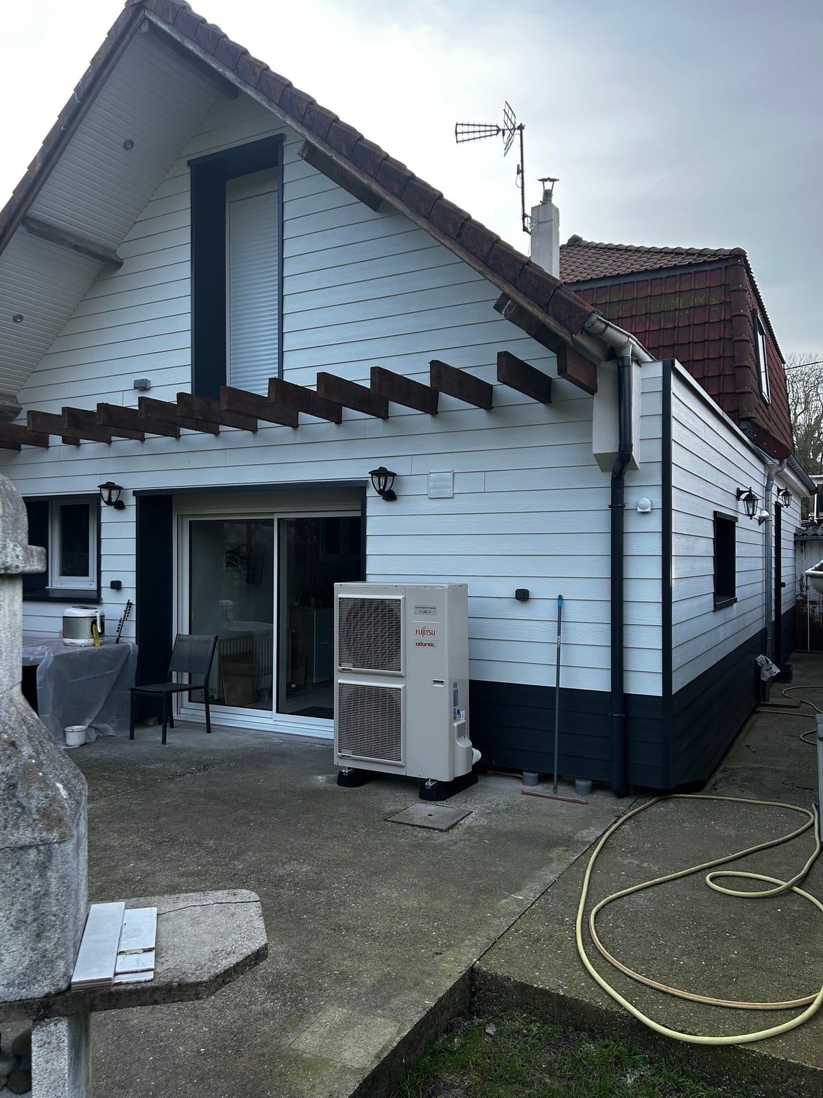 Pompe à chaleur Atlantic installée le long d'une maison avec bardage par Hapînov dans le Pas-de-Calais