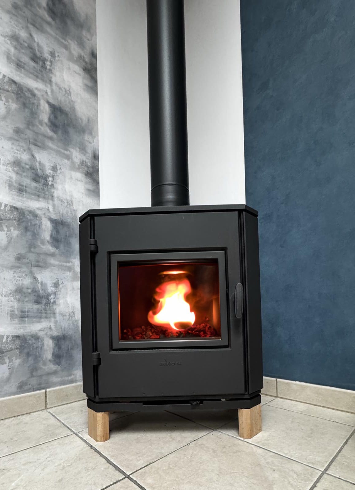 Poêle à bois noir compact sur pieds bois installé dans un séjour contemporain par Hapînov