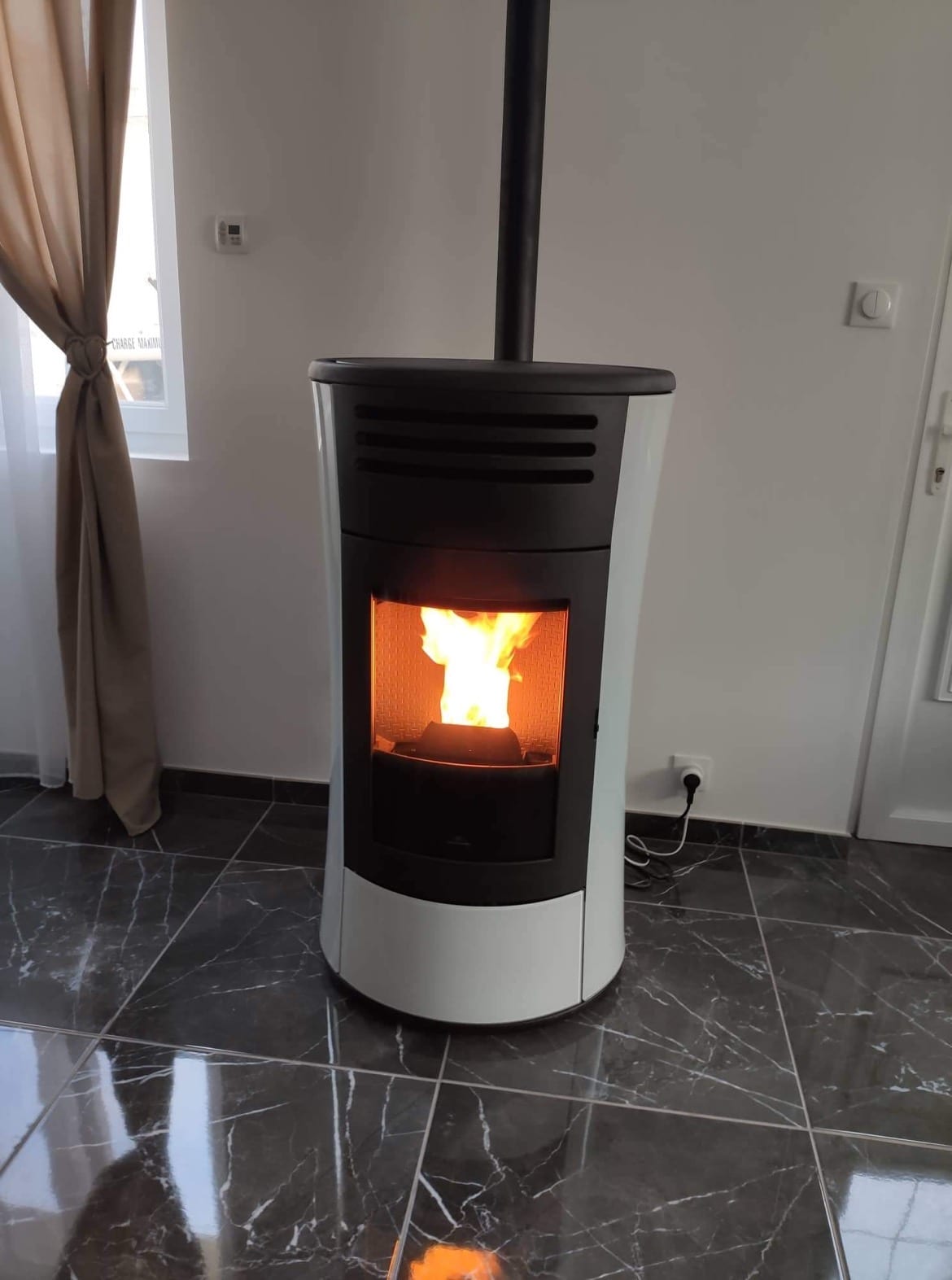 Poêle à granulés Edilkamin blanc installé dans un salon au sol marbré par Hapînov dans le Pas-de-Calais