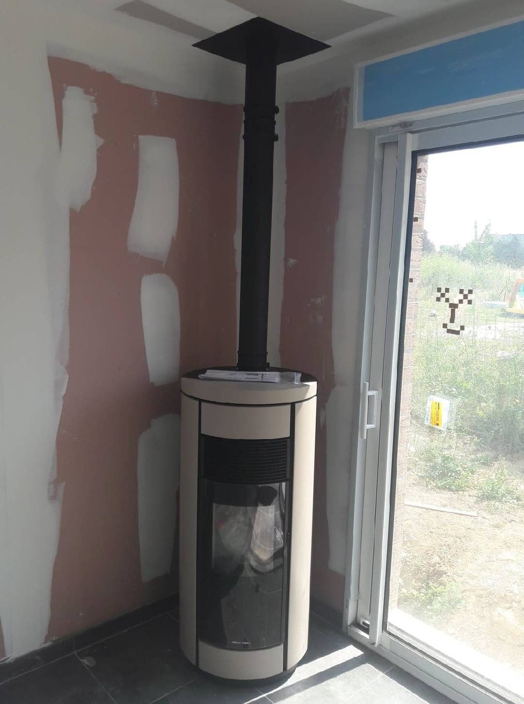 Poêle à granulés Jollymec cylindrique beige en cours d'installation par Hapînov