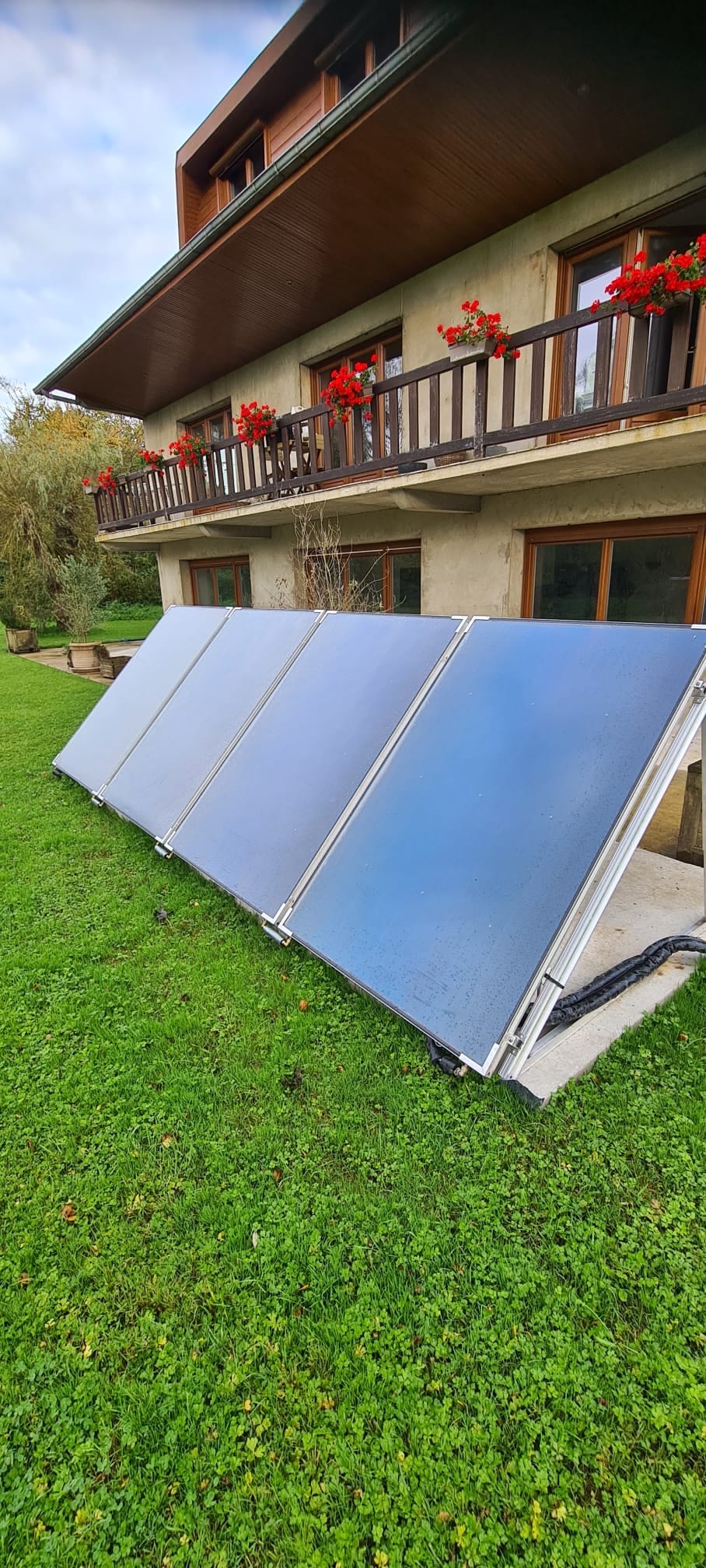 Panneaux solaires thermiques posés au sol devant un chalet par Hapînov dans le Pas-de-Calais