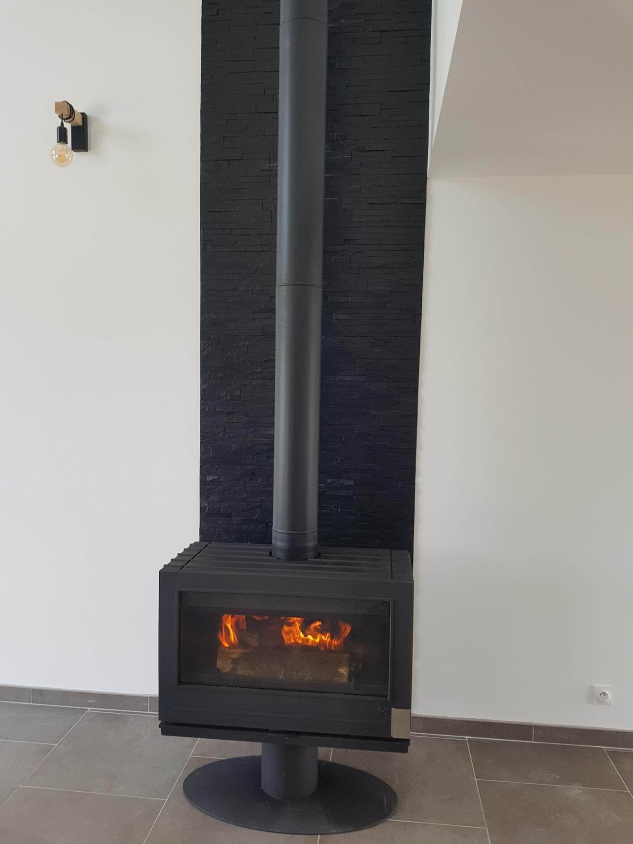 Poêle à bois design avec parement pierre noire installé par Hapînov dans le Pas-de-Calais